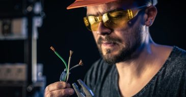 male-electrician-works-switchboard-with-electrical-connecting-cable_169016-18335